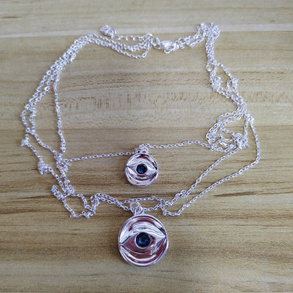 Multi-strand necklace displayed with evil eye charm. Alt: “UNOde50 Multi-Strand Chain Necklace with Evil Eye.”