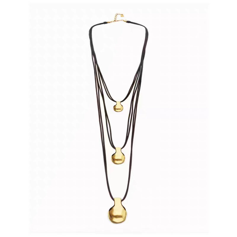 A multi-strand necklace featuring three layers of dark brown cord and three graduated gold-tone pendants, displayed against a plain white background.