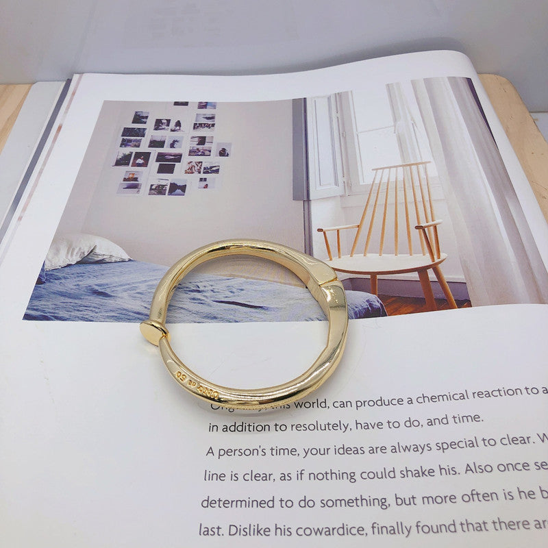  Nail-shaped bangle on neutral or edgy background. Alt: “UNOde50 Nail-Shaped Bangle Bracelet – Silver Sculptural Bangle.”