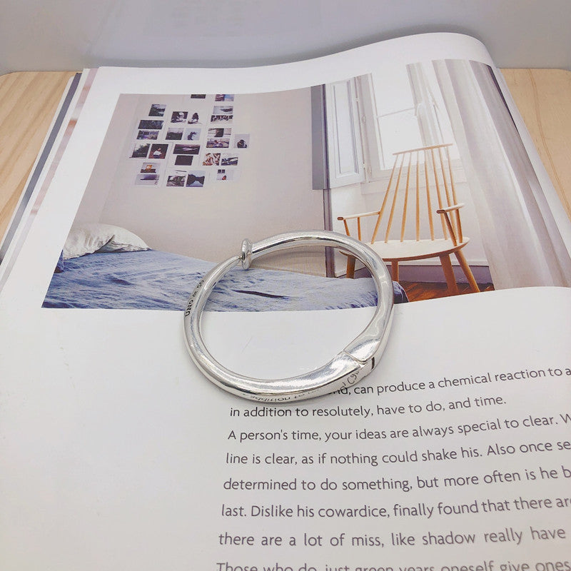  Nail-shaped bangle on neutral or edgy background. Alt: “UNOde50 Nail-Shaped Bangle Bracelet – Silver Sculptural Bangle.”