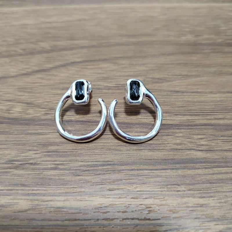 Needle-shaped earrings on neutral background. Alt: “UNOde50 Needle-Shaped Earrings – Sterling Silver-Plated Drops.”