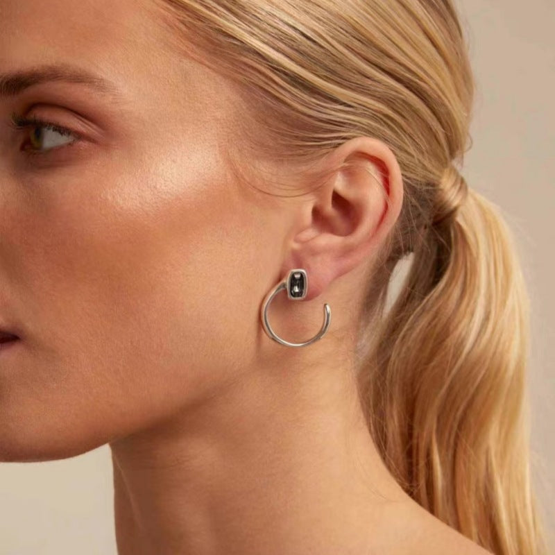 Needle-shaped earrings on neutral background. Alt: “UNOde50 Needle-Shaped Earrings – Sterling Silver-Plated Drops.”