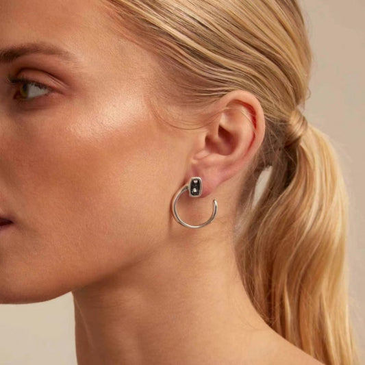 Needle-shaped earrings on neutral background. Alt: “UNOde50 Needle-Shaped Earrings – Sterling Silver-Plated Drops.”