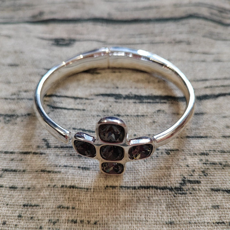 Silver bracelet with dark gemstones on a textured surface