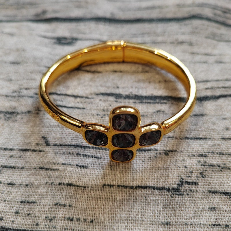 Gold bracelet with black stones on a textured surface