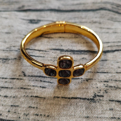 Gold bracelet with black stones on a textured surface