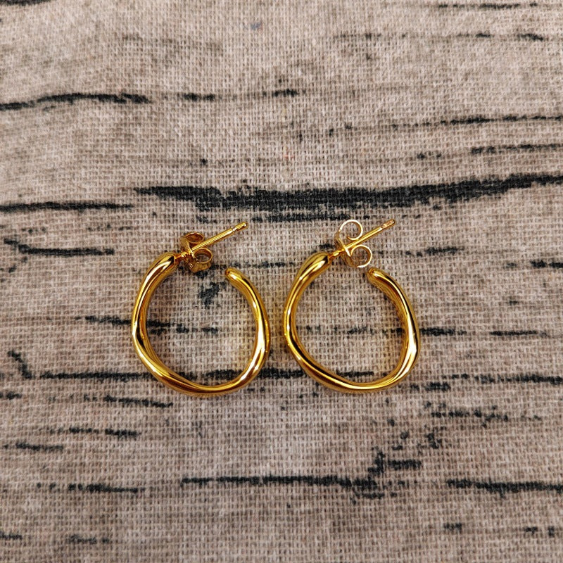 Hoop earrings on neutral or zen-inspired background. Alt: “UNOde50 Ohmmm Sculptural Hoop Earrings – Textured Silver Hoops.”