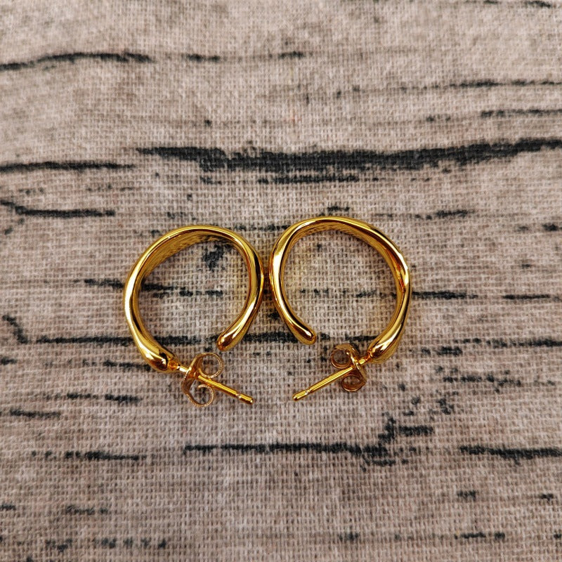 Hoop earrings on neutral or zen-inspired background. Alt: “UNOde50 Ohmmm Sculptural Hoop Earrings – Textured Silver Hoops.”