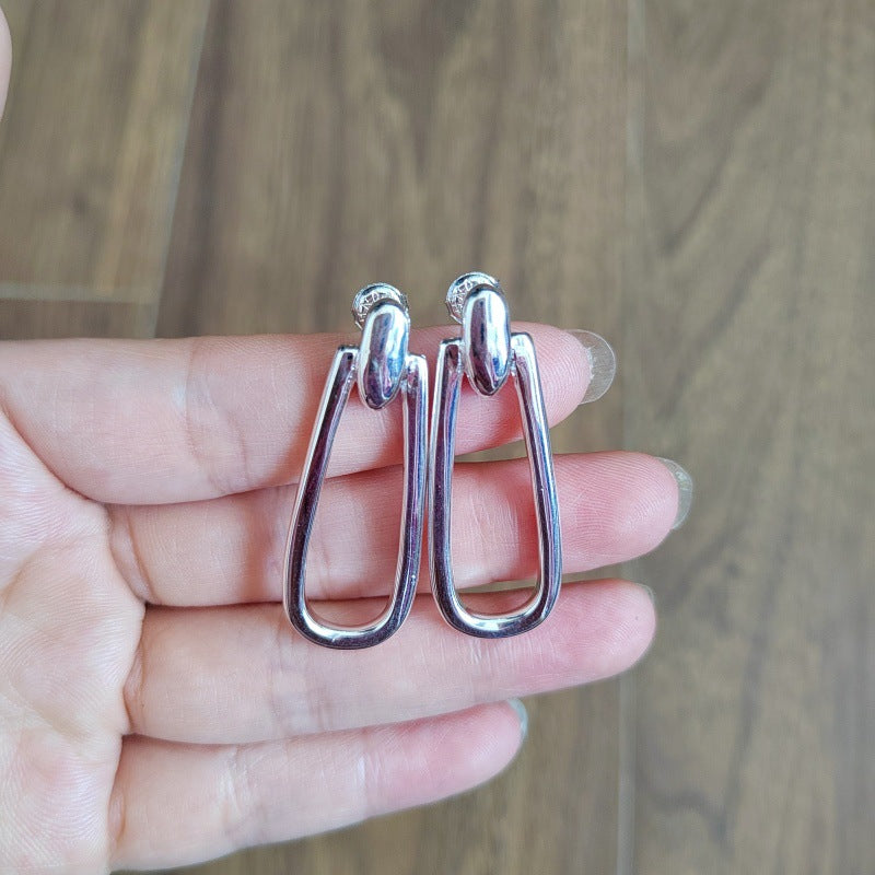Earrings on neutral or prosperity-themed background. Alt: “UNOde50 Prosperity Earrings – Silver Symbolic Drops.”