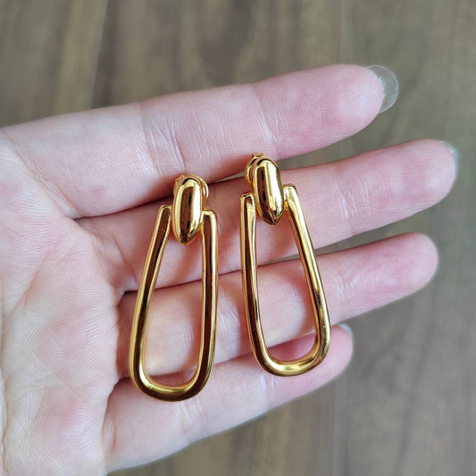 Earrings on neutral or prosperity-themed background. Alt: “UNOde50 Prosperity Earrings – Silver Symbolic Drops.”