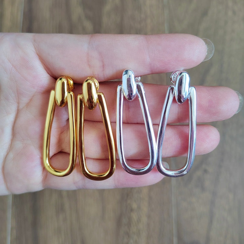 Earrings on neutral or prosperity-themed background. Alt: “UNOde50 Prosperity Earrings – Silver Symbolic Drops.”