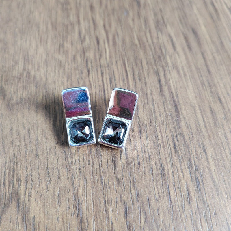 Rectangular studs on neutral background. Alt: “UNOde50 Rectangular-Shaped Stud Earrings – Silver Geometric Studs.”