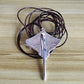 A silver pendant necklace featuring a stylized fish or eel design with a vertical bar, resting on a coiled dark brown leather cord, set against a light wood grain background.