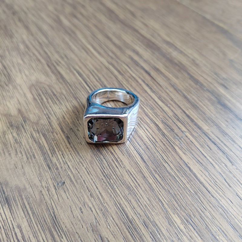 Square ring on neutral or geometric background. Alt: “UNOde50 Square Shape Ring with Crystal – Silver Geometric.”