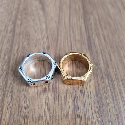 Two hexagonal metal rings, one silver-toned and one gold-toned, displayed side by side on a wooden surface.