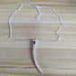 A silver-toned necklace with a curved, knife-like pendant featuring a small black rectangular accent, displayed on a light wood grain surface.
