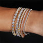 Stack of diamond bracelets on a wrist against a black background