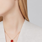 Red clover-shaped earrings and necklace on a model against a neutral background