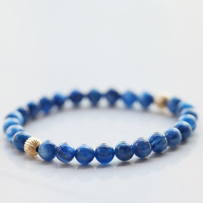 Blue beaded bracelet with gold accents on a light gray background