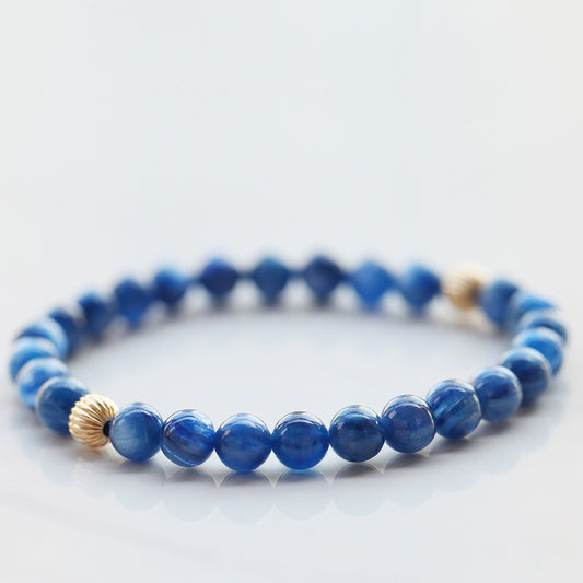 Blue beaded bracelet with gold accents on a light gray background