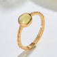 Gold ring with a green gemstone on a light gray background