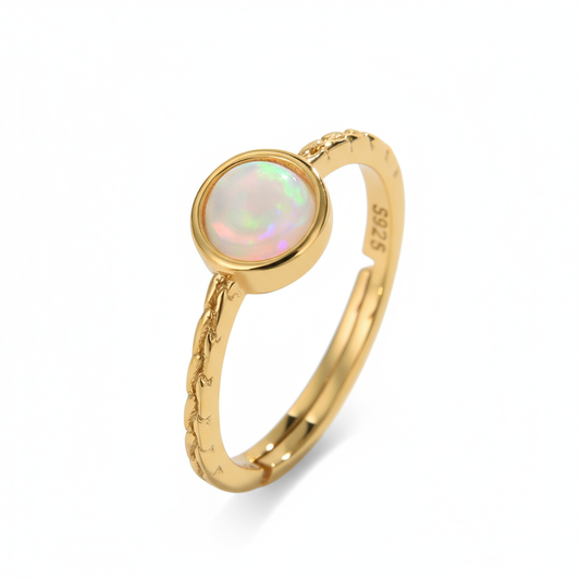 Gold ring with a colorful gemstone on a light background