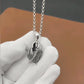 Silver necklace with a feather pendant held by a gloved hand against a blurred background