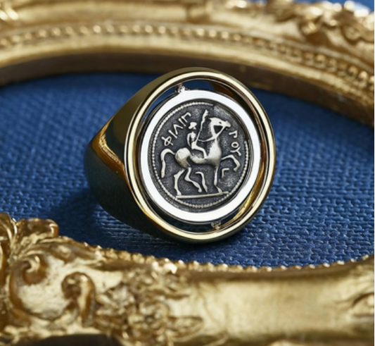 Gold ring with a silver emblem on a blue fabric background