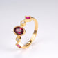 Gold ring with red gemstones on a light gray background