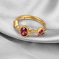 Gold ring with red gemstone and small diamonds on a gray fabric background