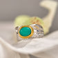 Silver ring with a green gemstone on a white surface