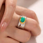 Silver ring with a green gemstone on a finger against a neutral background