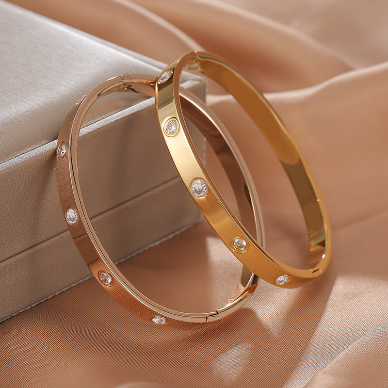 Gold hoop earrings with embedded stones on a beige fabric background