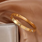 Gold bracelet with diamond accents on a brown fabric background