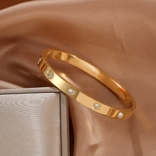 Gold bracelet with embedded diamonds on a brown fabric background