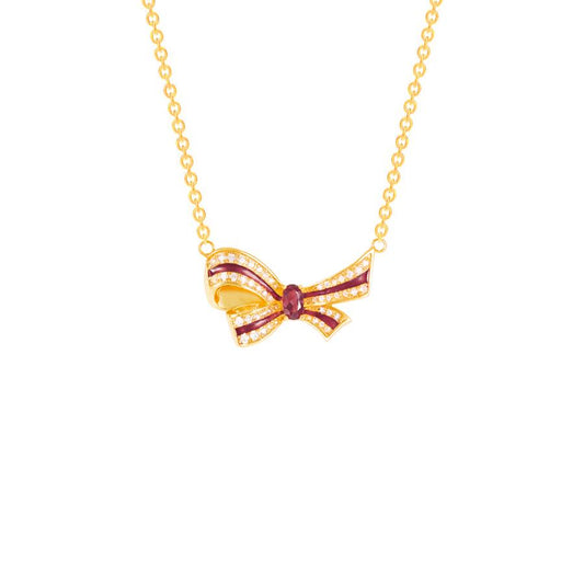 Gold bow-shaped necklace with a red gemstone on a white background