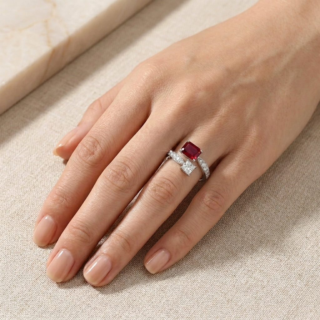 Real-life hand view of a model displaying an alternative bridal ruby and princess-cut crystal Toi et Moi ring under soft light.