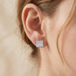 Model wearing Art Deco baguette and round moissanite stud earrings on earlobe.