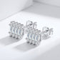 Pair of Art Deco baguette and round moissanite stud earrings displayed on plain surface.