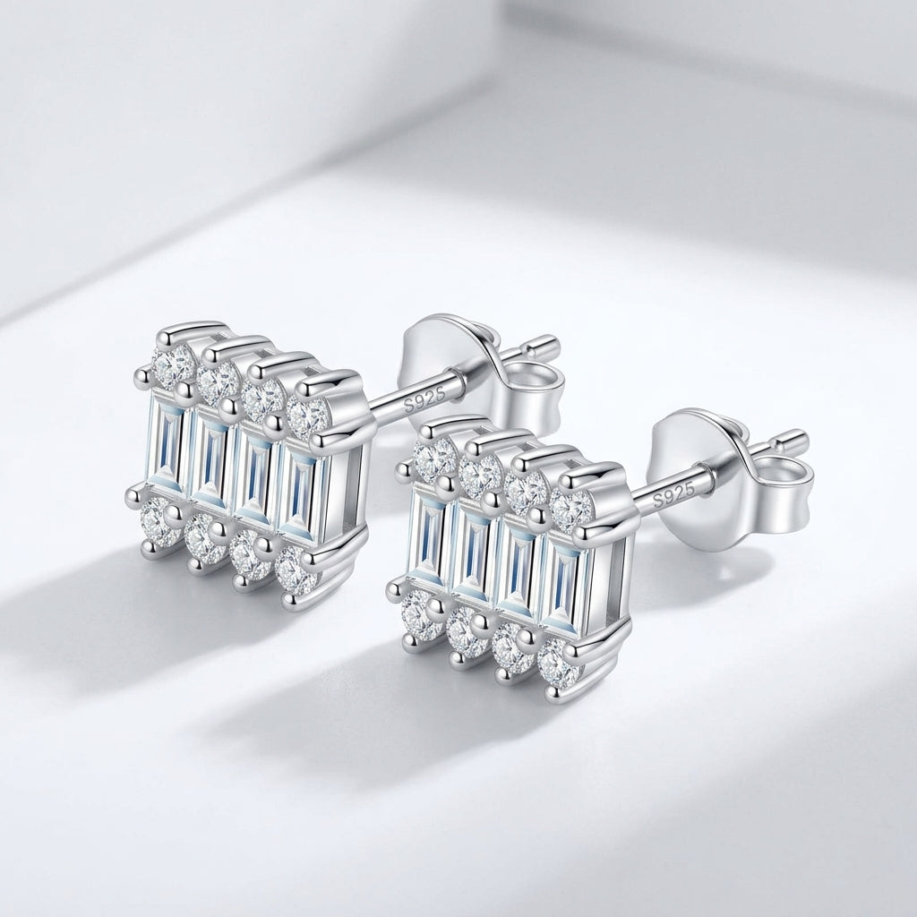 Pair of Art Deco baguette and round moissanite stud earrings displayed on plain surface.