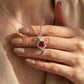 High-angle close-up view of a model wearing the artistic ruby treble clef pendant necklace under soft studio lighting.