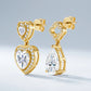 Angled view of mismatched gold moissanite drop earrings with heart and pear cuts.