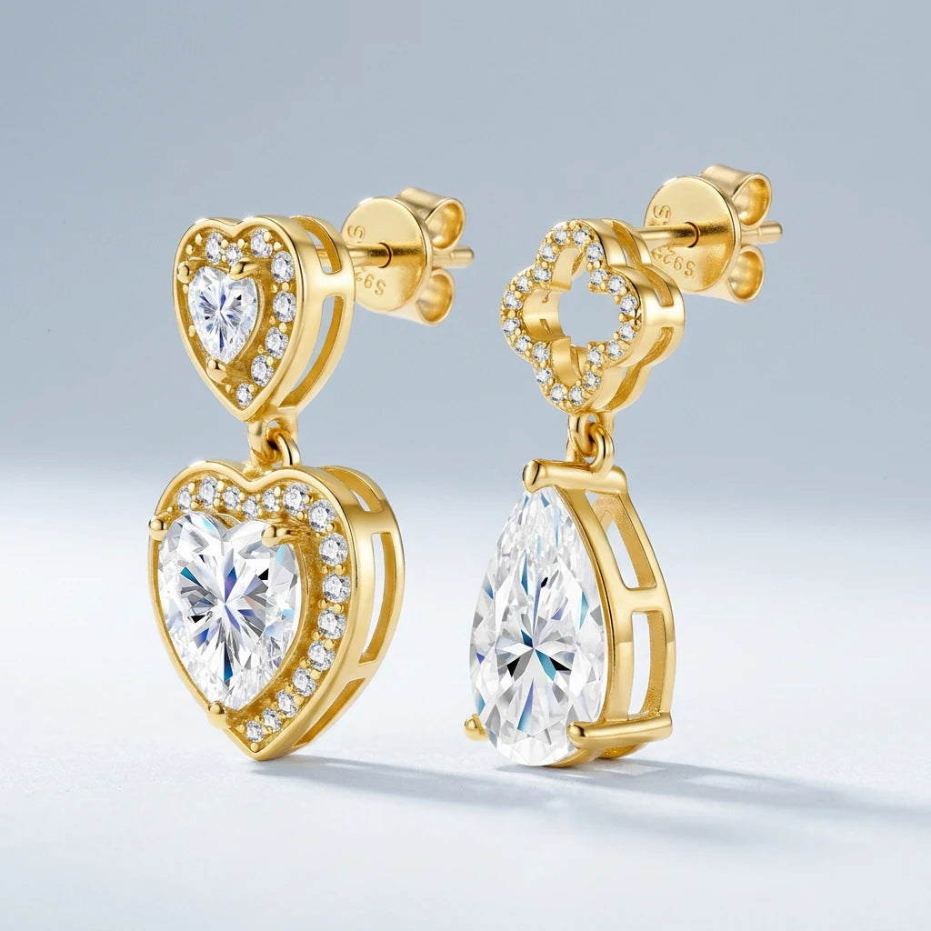 Angled view of mismatched gold moissanite drop earrings with heart and pear cuts.