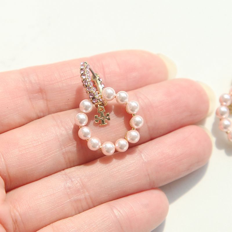 Close-up macro view of authentic moondance pearl hoop earrings held in a person's palm showing real-world scale.