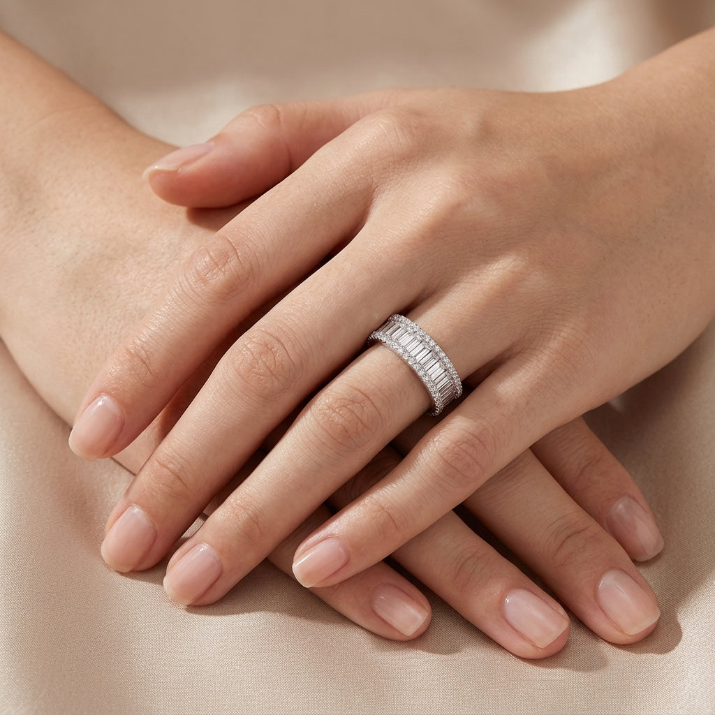 Close-up view of model wearing wide baguette moissanite eternity ring on hand.
