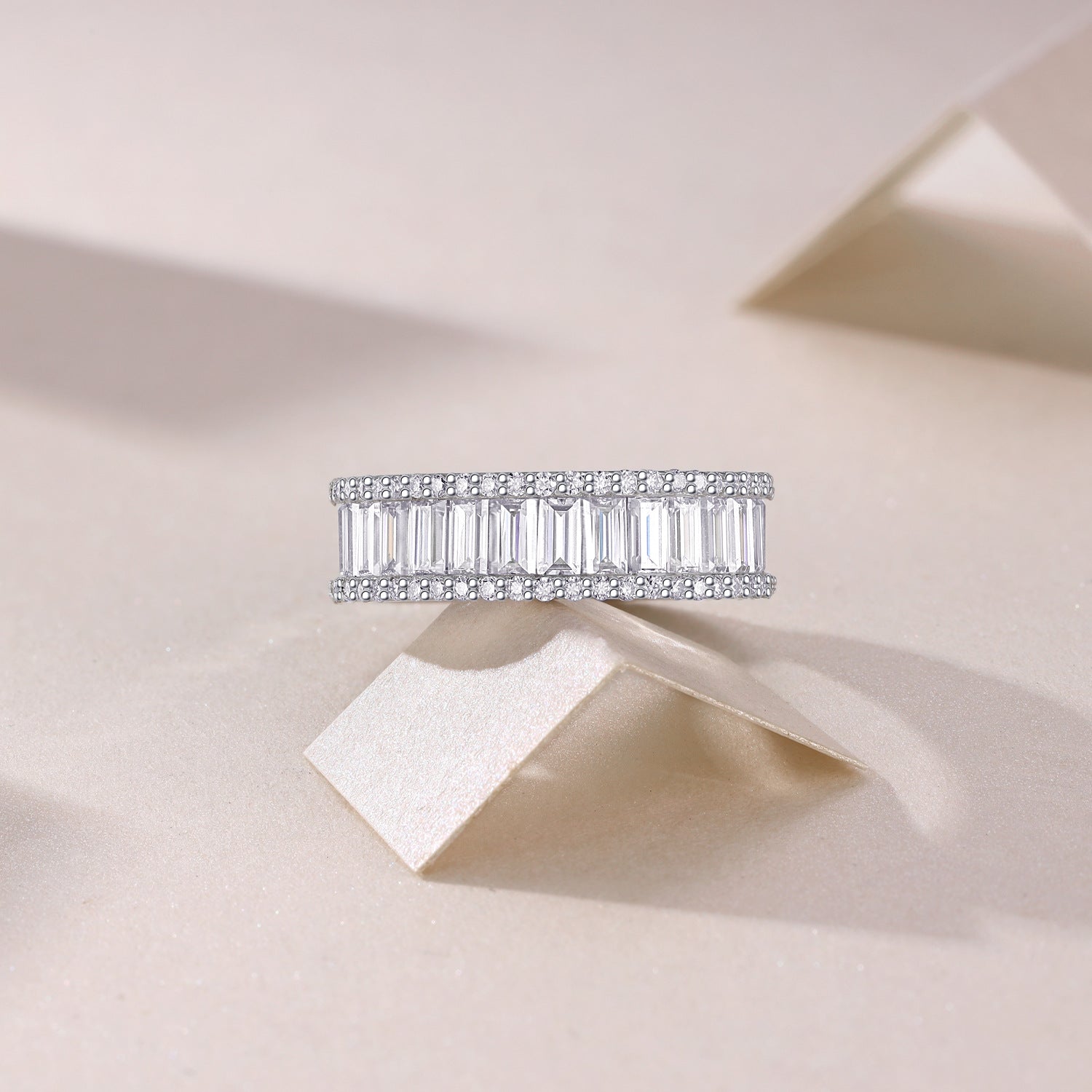 Baguette moissanite double halo eternity band resting on neutral background.