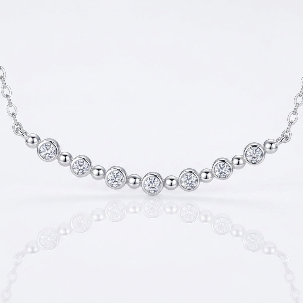 Close-up view of bezel set graduated moissanite and polished bead spacers on smile bar.