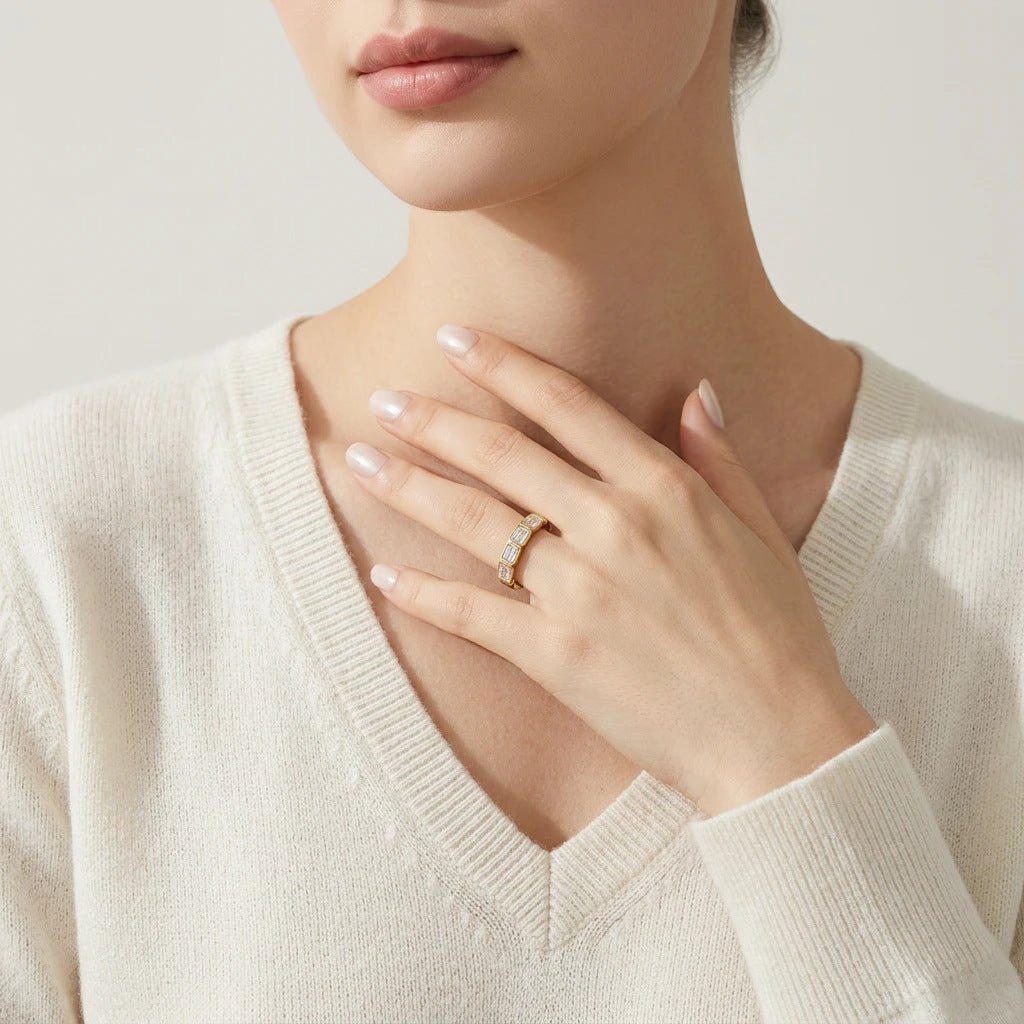 Model wearing the gold bezel set emerald cut moissanite stacking band in a lifestyle portrait.