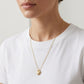 Model adjusts her hair wearing Bold Heirloom Heart Locket, showing the pendant in motion