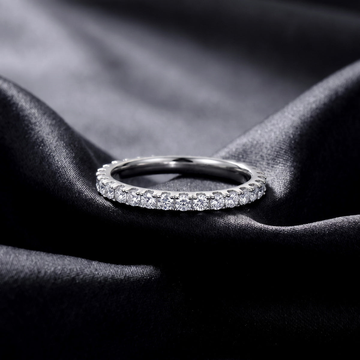 Brilliant full eternity lab grown diamond band ring lying flat on dark black silk fabric